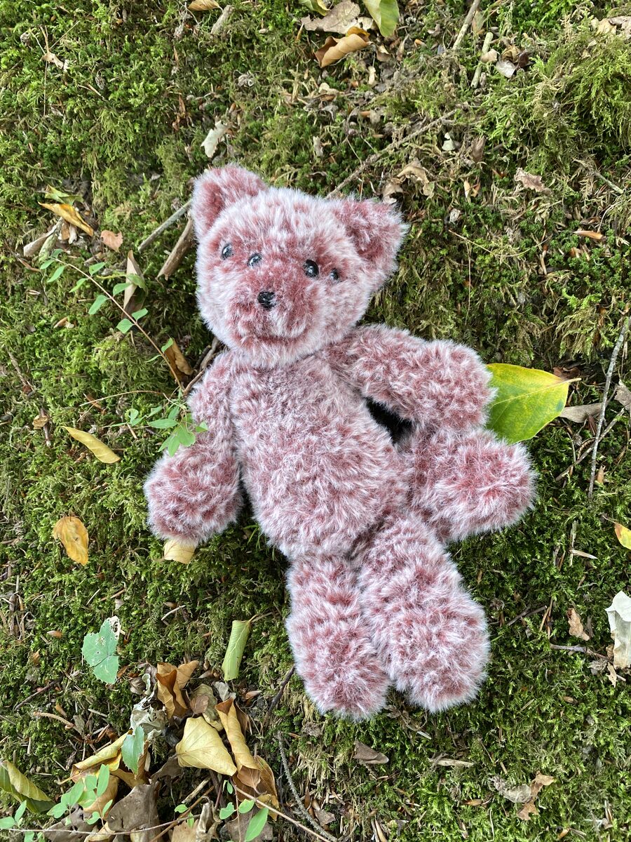 Arden, a rose-and-cream wolf-fox spirit, sitting in soft grass.